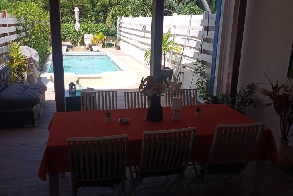 a red table with chairs and a swimming pool at Beach house with nice private pool ,baie orientale in Orient Bay