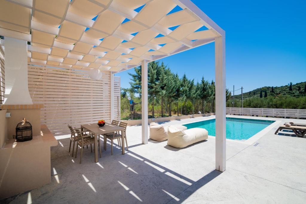 un patio con tavolo, sedie e piscina di Spartakos Luxury Villa 6 a Plános