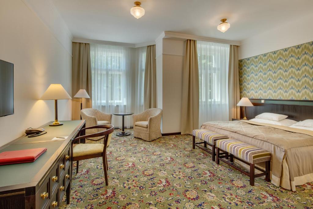a hotel room with a bed and a desk and chairs at Hotel Savoy Prague in Prague