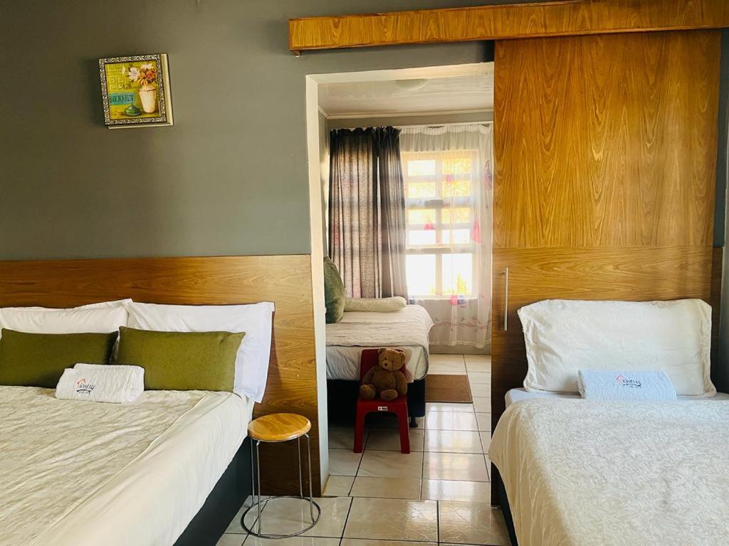 um quarto com 2 camas e uma janela com um urso de peluche em Homey Guesthouse em Gaborone