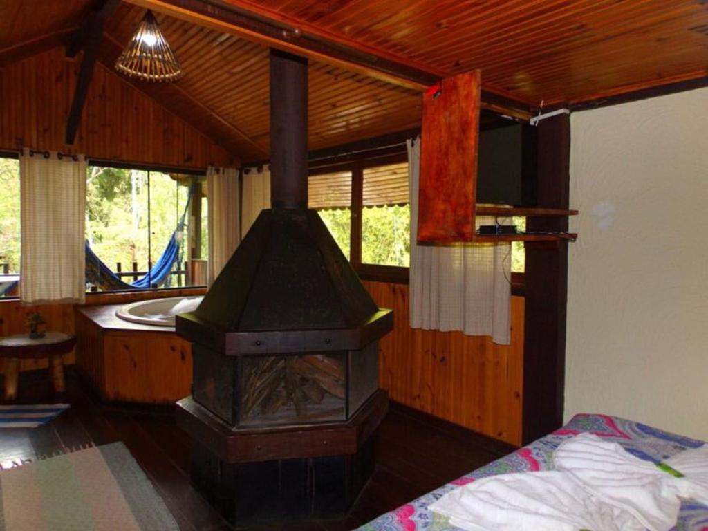 um fogão a lenha num quarto com uma cama em Pousada Santa Clara em Visconde de Mauá