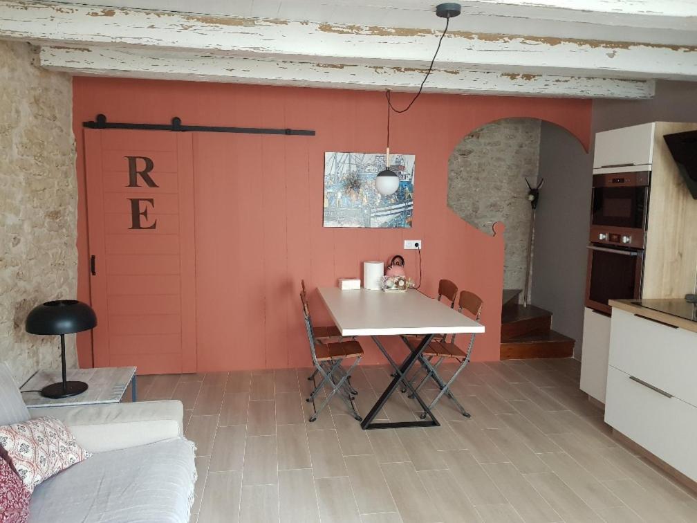 a kitchen with a table and a red garage door at ilederesibois in Les Portes