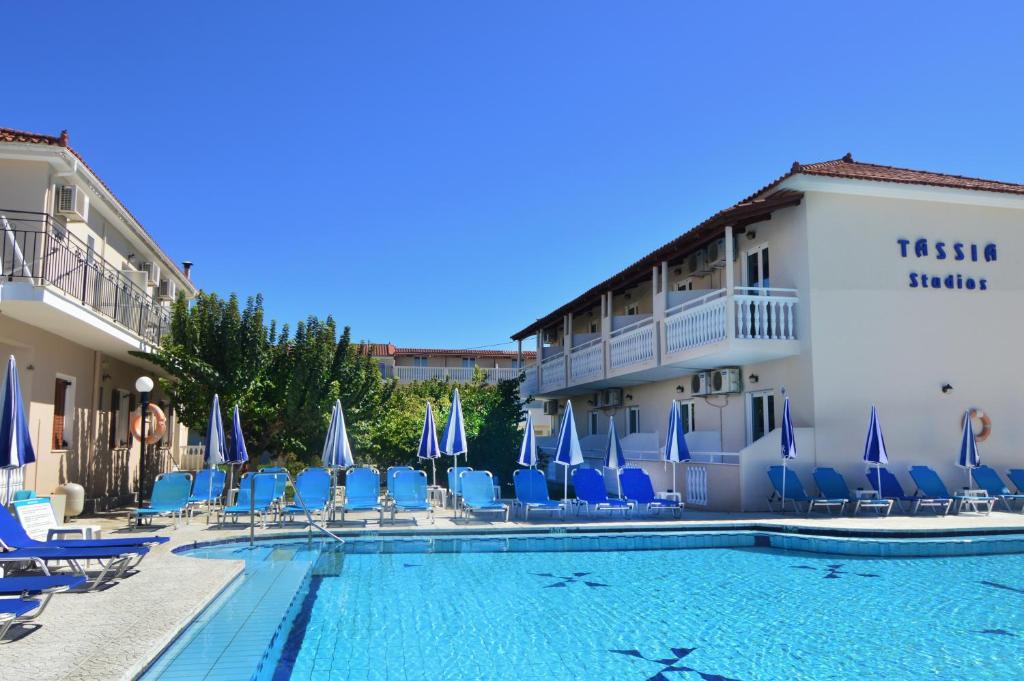 a hotel with a swimming pool and chairs and a building at Hotel Tassia for families & couples in Laganas