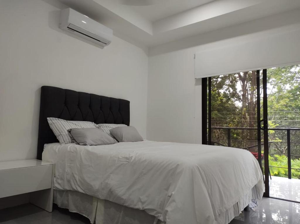 a white bedroom with a bed and a large window at Hakuna in San Juanillo