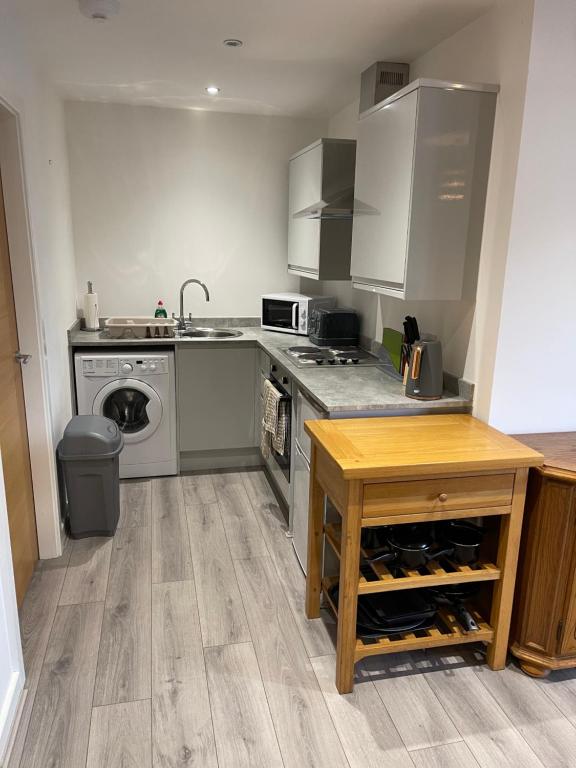 a kitchen with a stove and a sink and a table at Lovely 4 bed apartment in centre of Formby in Formby
