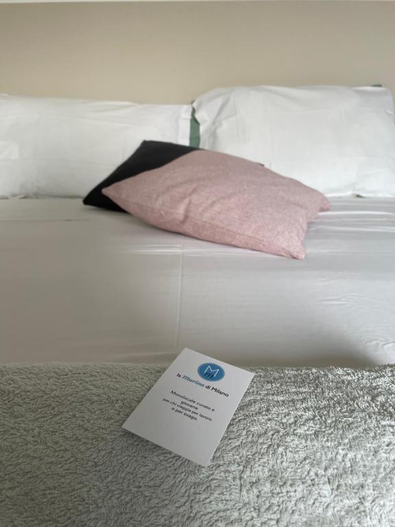 Una cama blanca con un cartel encima. en La Marina di Milano - Pier Lombardo, en Milán