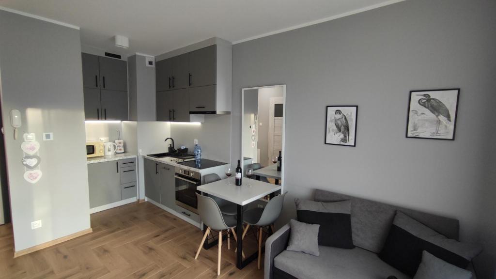 a kitchen and living room with a couch and a table at Apartament Orla 47F Perłowa Dolina in Bydgoszcz