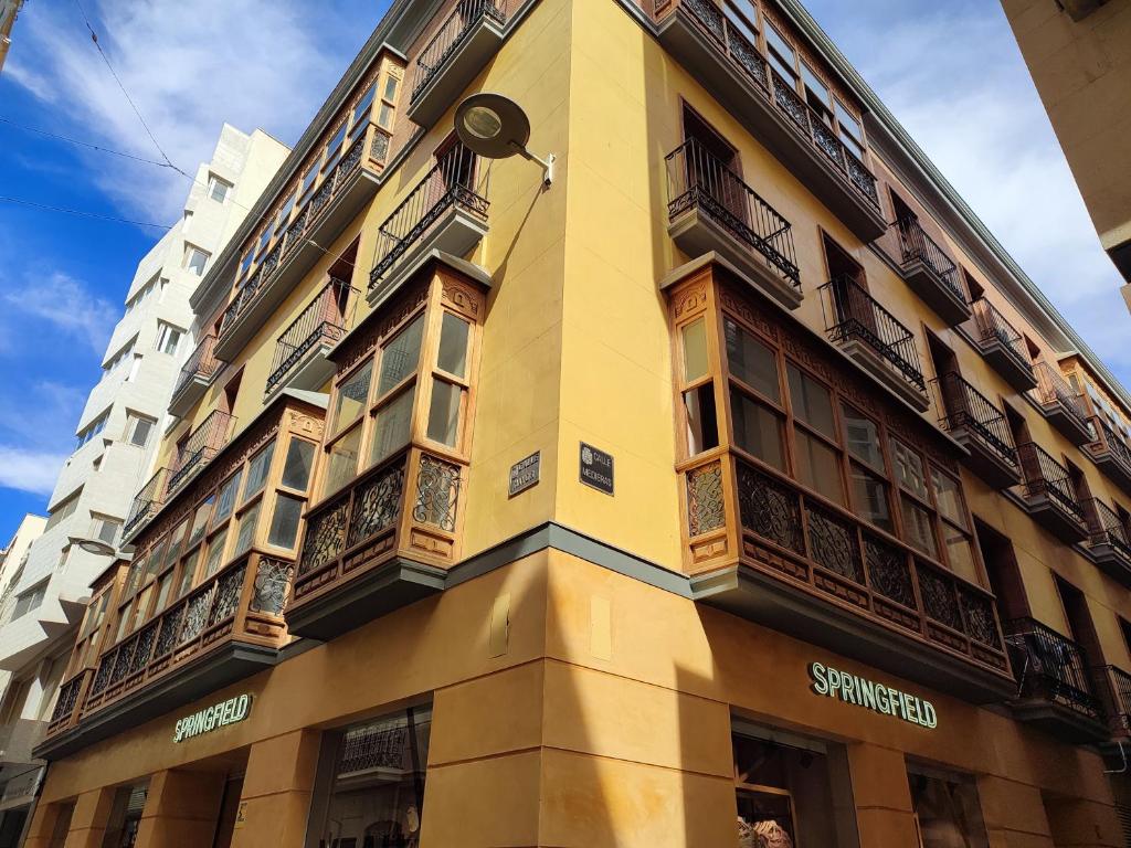 un bâtiment jaune avec des balcons sur son côté dans l'établissement CARTAGENAFLATS, Apartamentos Calle Mayor, CITY CENTER, à Carthagène