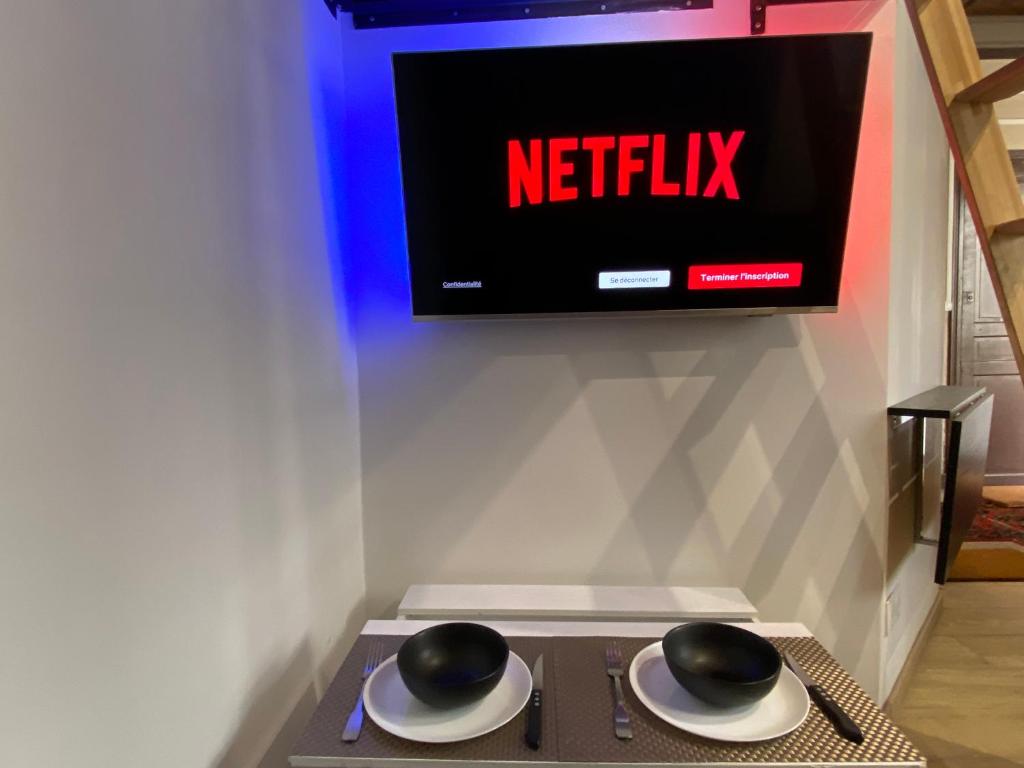 deux chapeaux sur une table avec une télévision sur un mur dans l'établissement Cozy studio Paris 5ème métro Jussieu/Sorbonne, à Paris