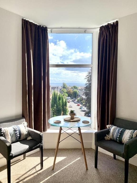a living room with a table and a large window at Seaview Richmond Terrace in Swansea