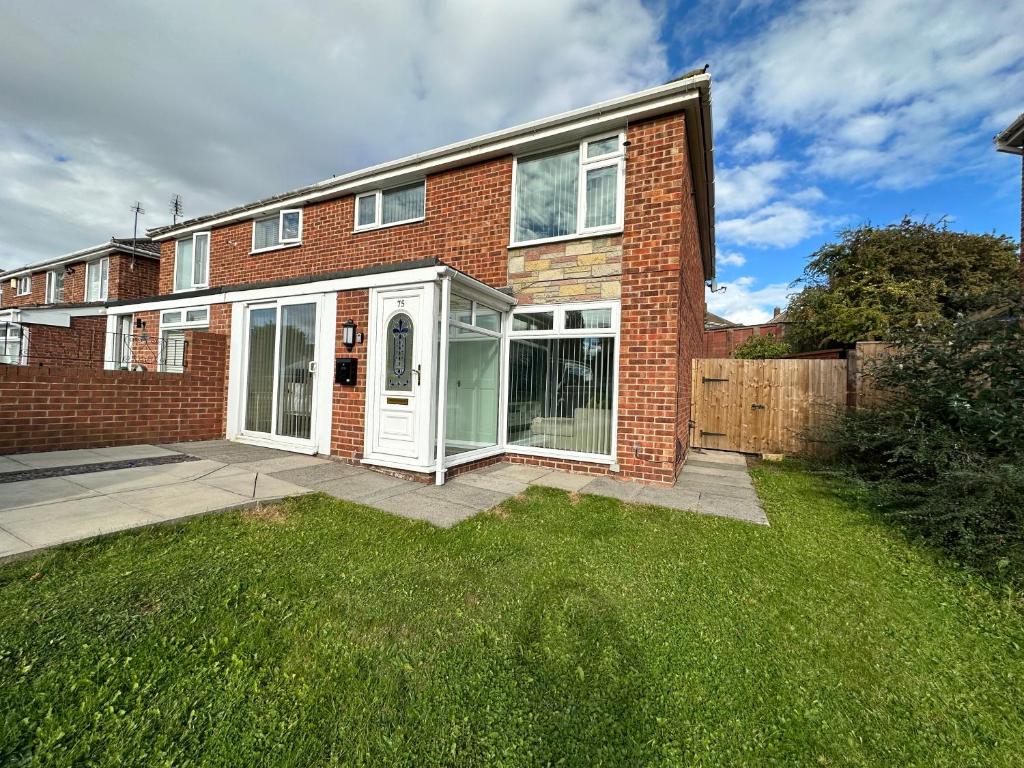 a brick house with white doors and a yard at Spacious and stylish 3-bed home ideal for families in Stockton-on-Tees