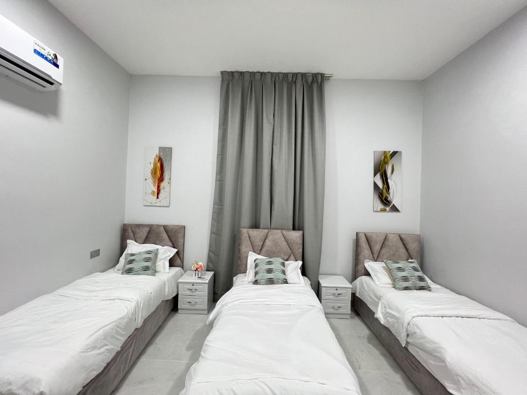 two beds in a room with white walls at alsaif camp in Bidiyah
