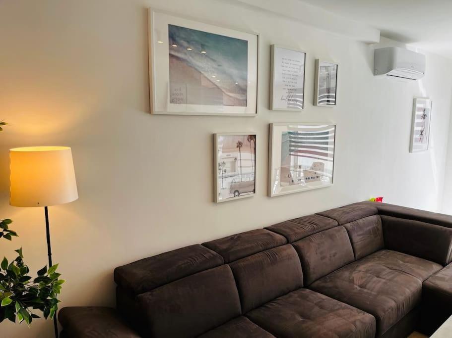 uma sala de estar com um sofá castanho e fotografias na parede em Sliema, Apt7, Stylish 2 Bedroom Apartment with Parking em Sliema