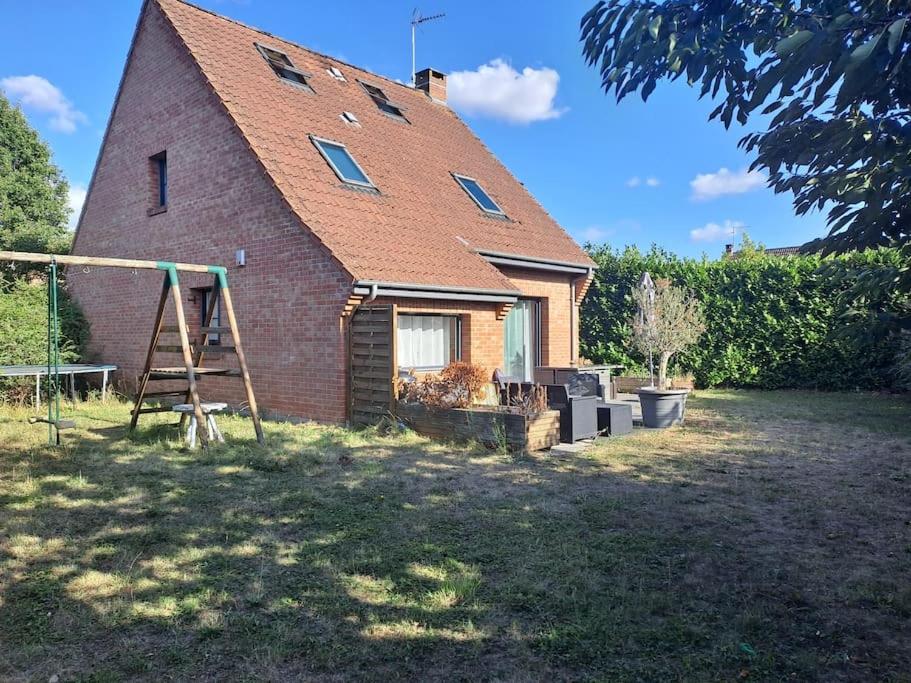 a small brick house with a playground in front of it at Villa individuelle 5 mn Lille centre Chr/eurasante in Haubourdin