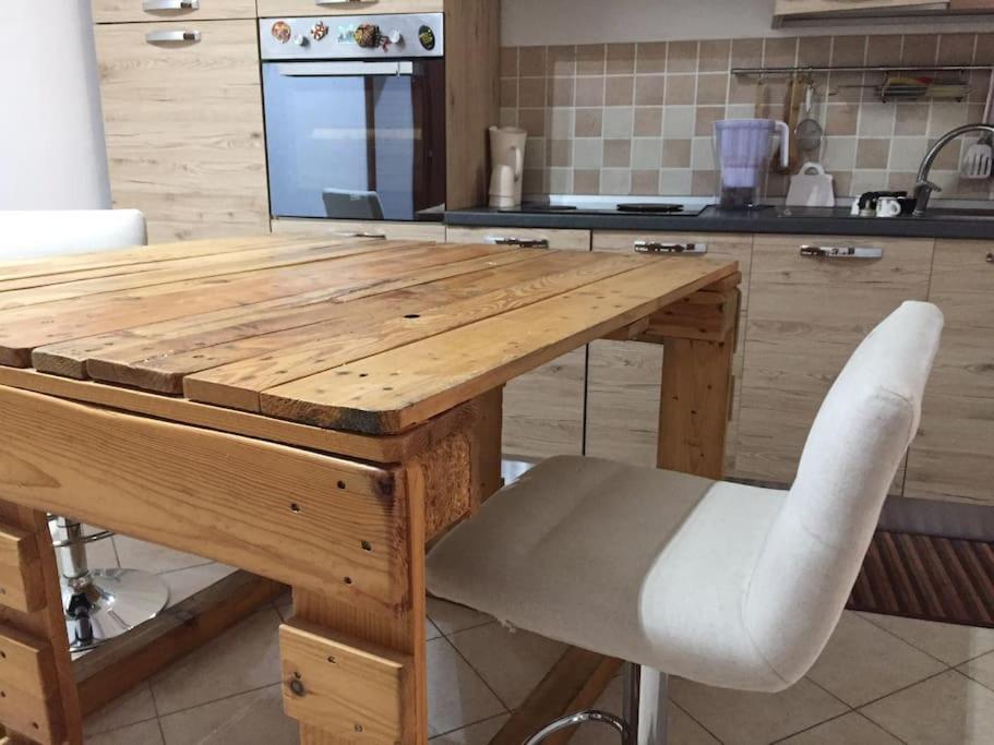 a wooden table with a white chair in a kitchen at GIARDINI VERDI Intero appartamento in Muravera