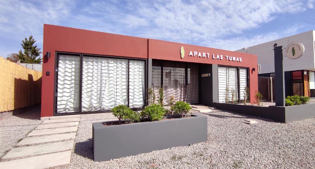 um edifício vermelho com plantas em frente em Apart Las Tunas Carmelo em Carmelo