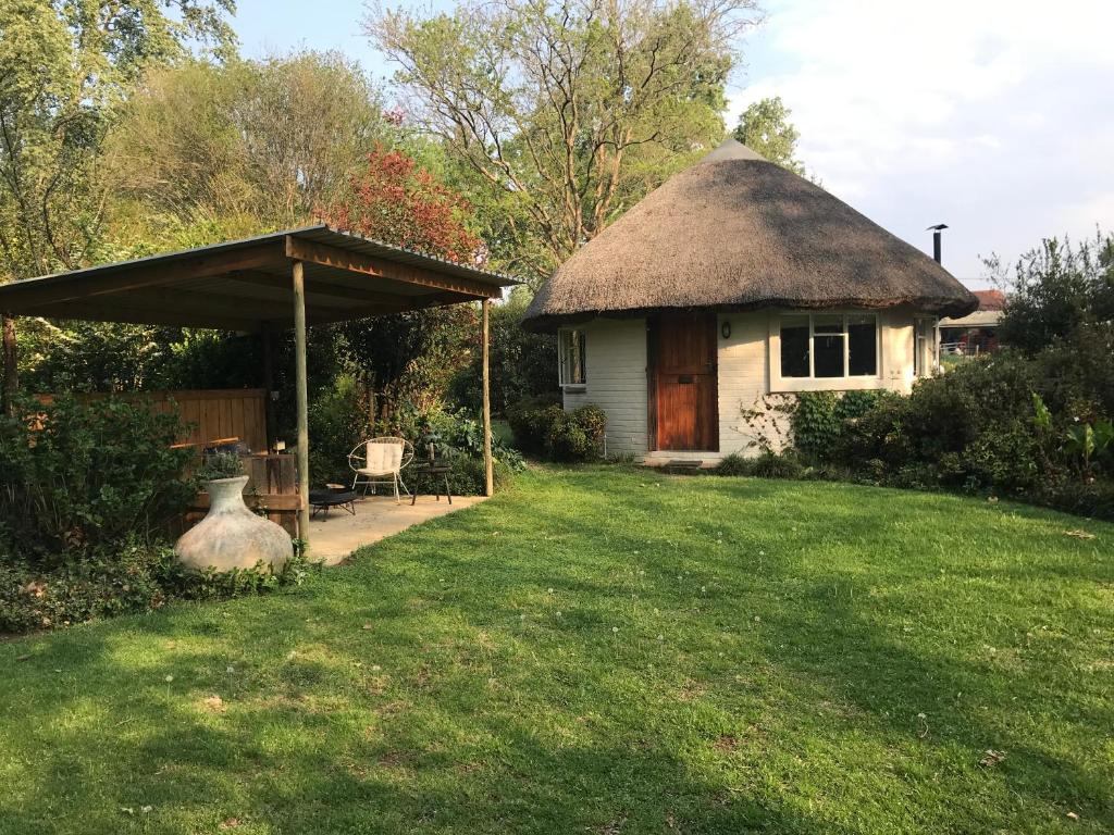 a small house with a thatch roof and a yard at Gartmore Guest Farm in Howick