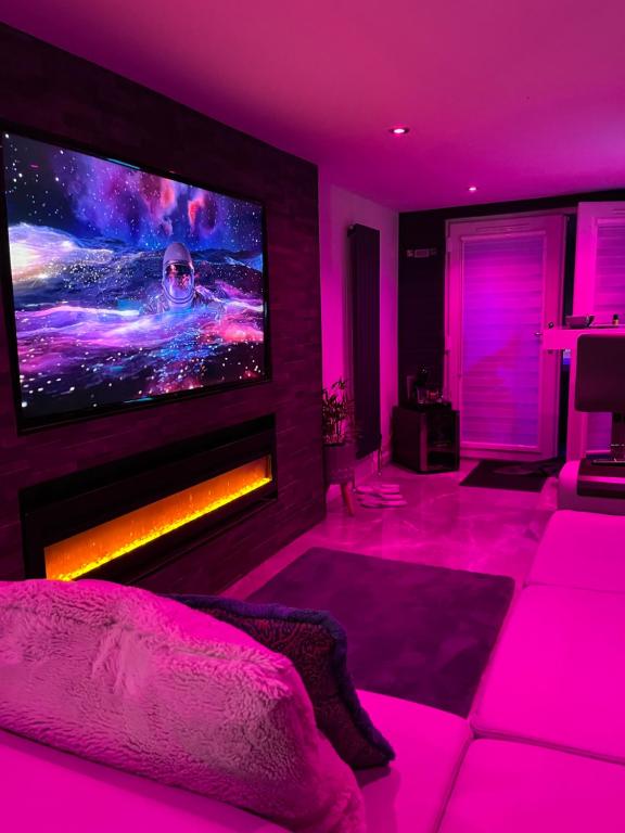 a living room with a large tv and pink lighting at The_Spa_Cave in Murroes
