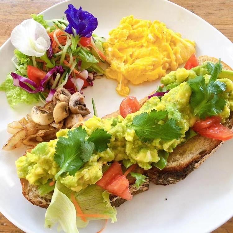 a white plate with a sandwich with eggs and a salad at Metteyya Healing House in Ubud