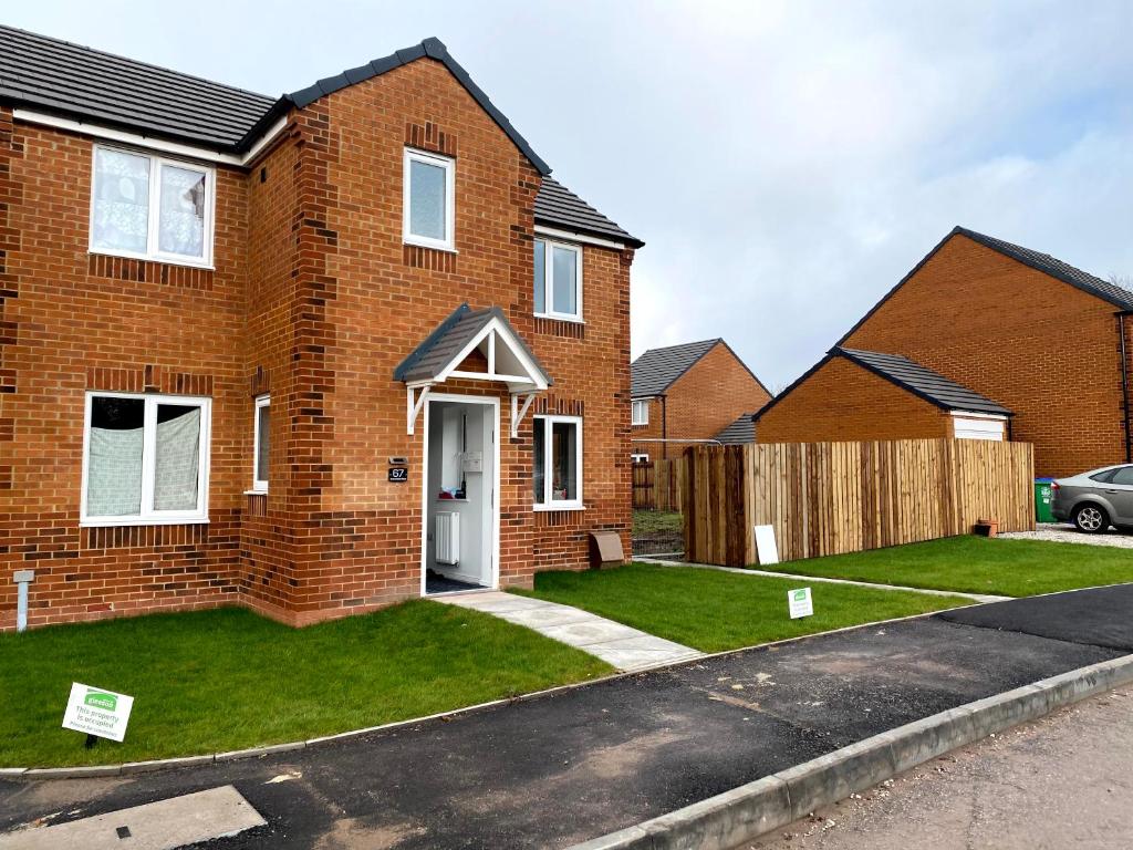 a brick house with a green lawn in front of it at Loving Home to Stay with Rear Garden and Patio in Rochdale