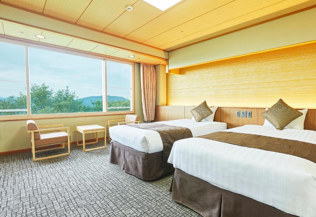 KAMENOI HOTEL Fukui في فوكوي: غرفة فندقية بسريرين ونافذة كبيرة
