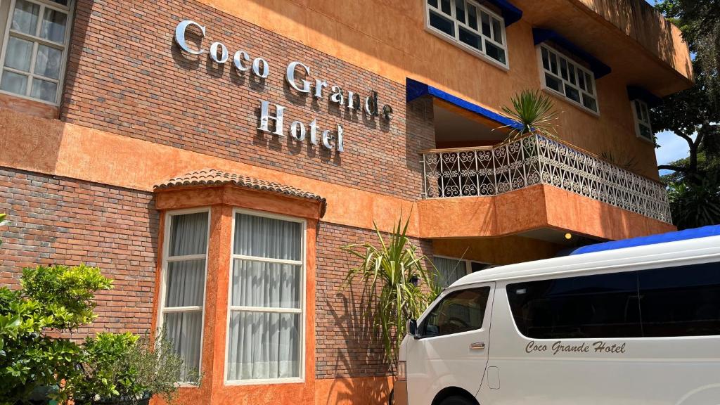 een wit busje geparkeerd voor een bakstenen gebouw bij Coco Grande Hotel in Dumaguete