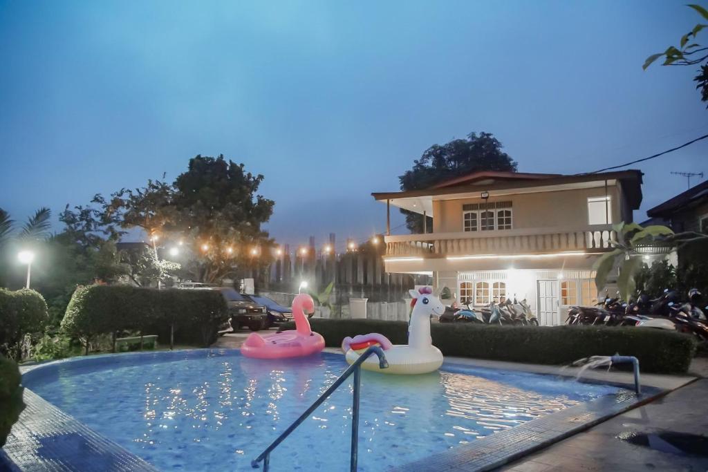 a swimming pool with two inflatable flamingos in front of a house at RedDoorz near Taman Safari 2 in Bogor