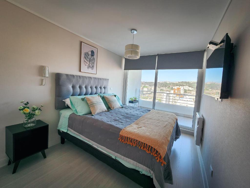 a bedroom with a large bed with a large window at Cómodo departamento familiar a pasos de la playa in Viña del Mar