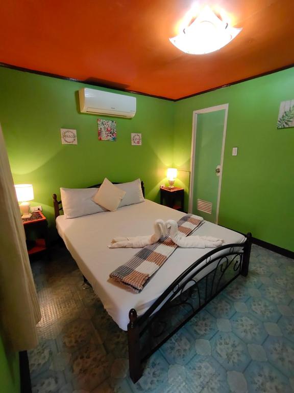 um quarto com uma cama com paredes verdes em Adrianas Place Hostel em Panglao