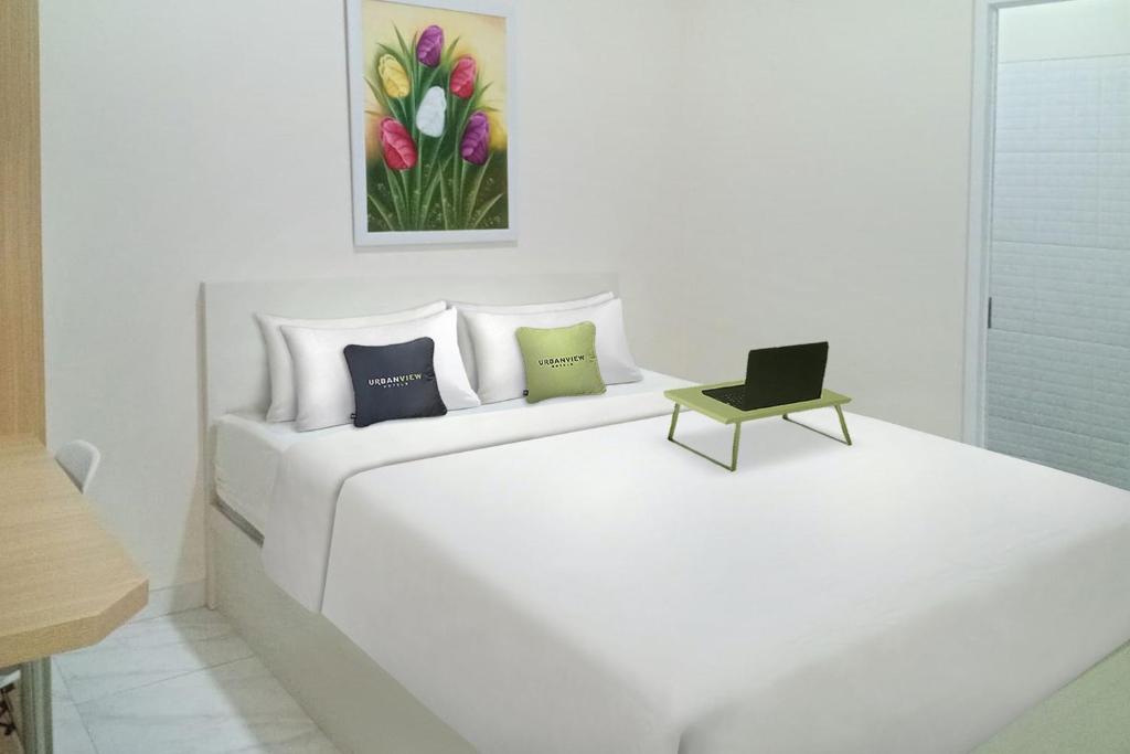 a white bedroom with a white bed with a laptop on it at Urbanview Syariah Utami Inn Garut by RedDoorz in Garut