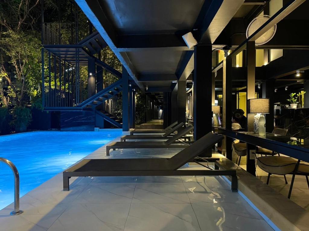 Poolside loungers line a covered terrace beside the illuminated pool.