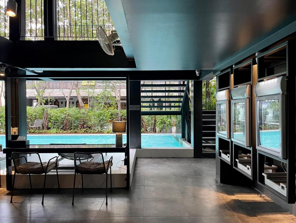 A pool-facing lounge has two chairs, a table, and self-service drink stations.