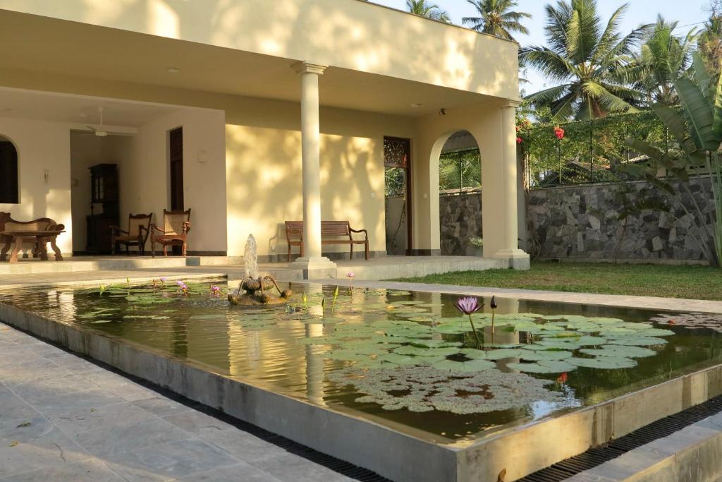 a pond with lilies in front of a house at Khomba Lodge in Tangalle