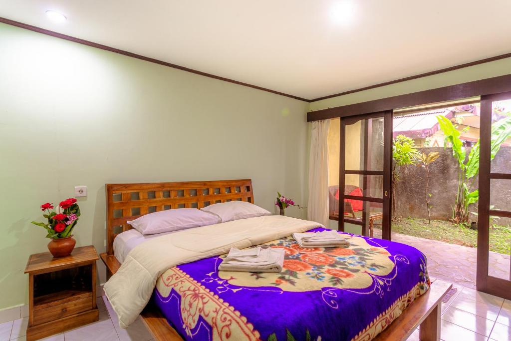 a bedroom with a large bed with a purple blanket at Pacung Indah Hotel & Restaurant by ecommerceloka in Bedugul