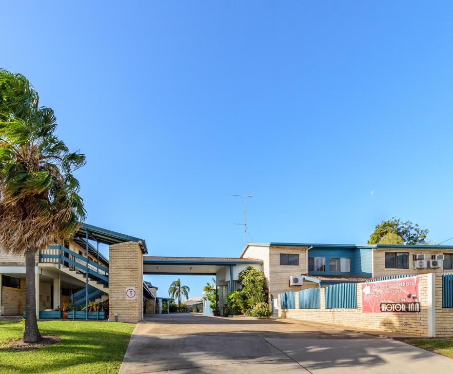 a building with a palm tree in front of it at Gladstone Palms Motor Inn in Gladstone