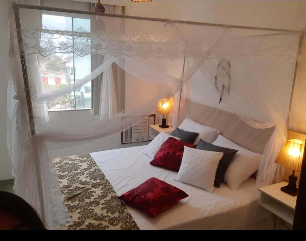 a bedroom with a white bed with red pillows at Flat Bela Vista in Macaé