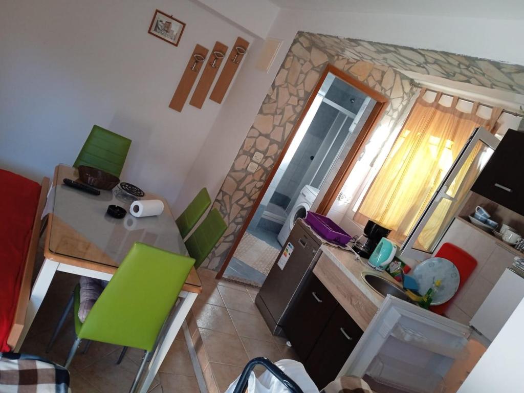 kuchnia ze stołem i zielonymi krzesłami w pokoju w obiekcie Apartmani L&Z w Petrčane
