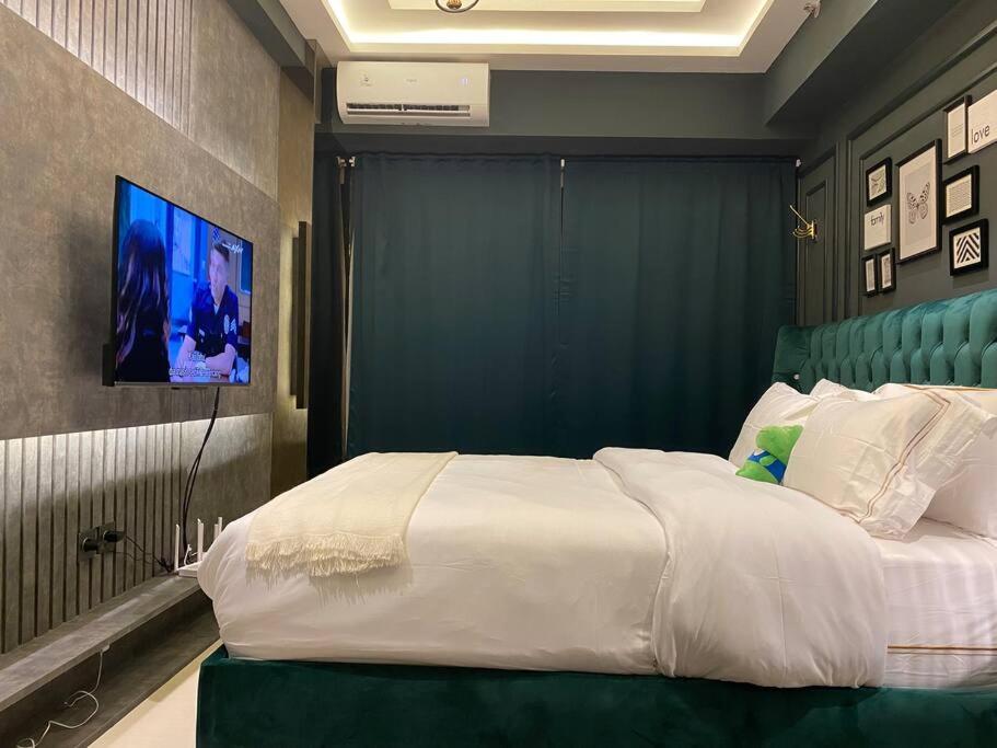 een slaapkamer met een groot bed en een tv aan de muur bij Du LoVeRe at Anderson Apartment in Lontar