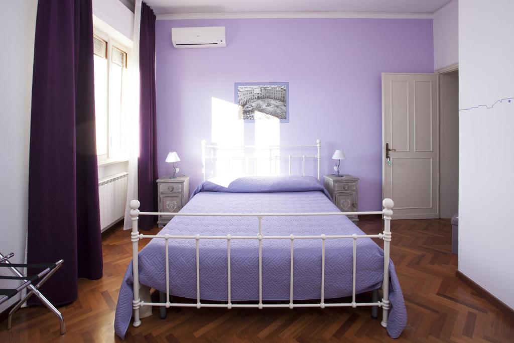 a bedroom with a bed with purple walls and a window at B&B Cento Passi Dalle Mura in Lucca