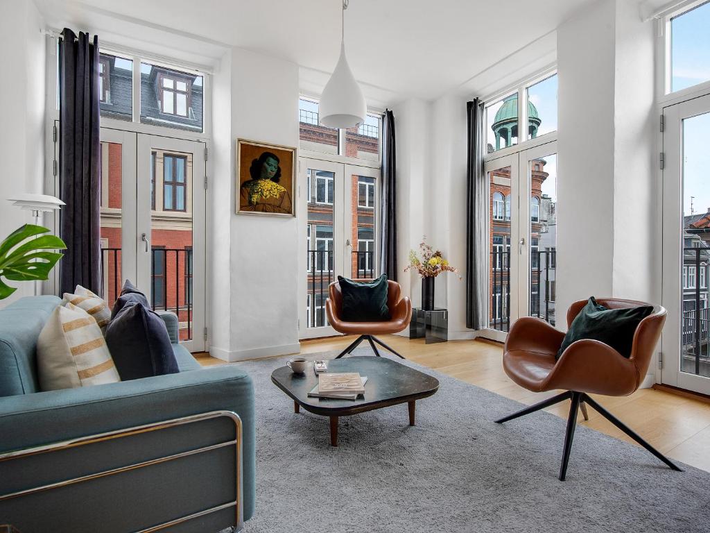 a living room with a couch and chairs and windows at Sanders Leaves - Pleasant Four-Bedroom Apartment In Downtown Copenhagen in Copenhagen