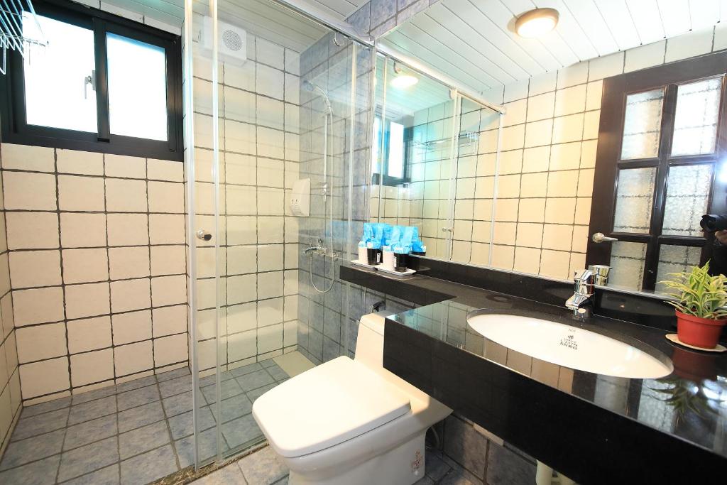 a bathroom with a toilet and a sink and a mirror at Qixingtan Xinghai B&amp;B in Dahan
