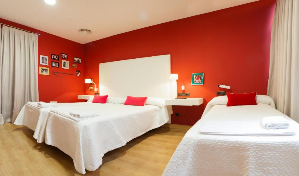 2 camas en una habitación con paredes rojas en Ritual Alameda Sevilla, en Sevilla