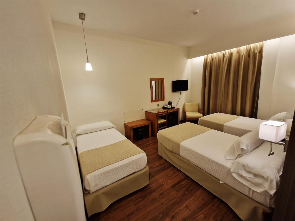 a hotel room with two beds and a desk at Hotel de Francia y París in Cádiz