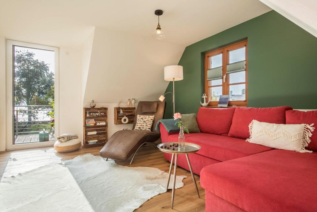 a living room with a red couch and a green wall at Seekind in Kressbronn am Bodensee