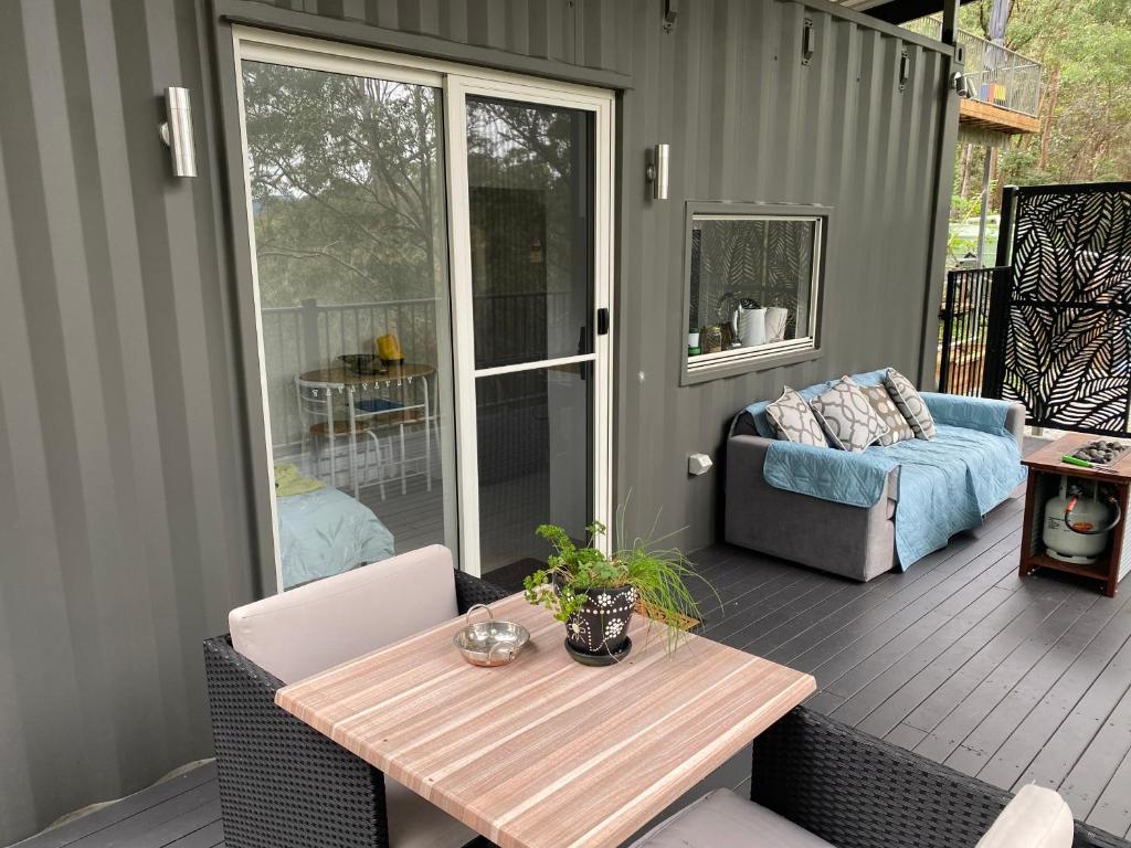 een patio met een tafel en een bank op een terras bij 424 Trees Tiny Home in Tallebudgera