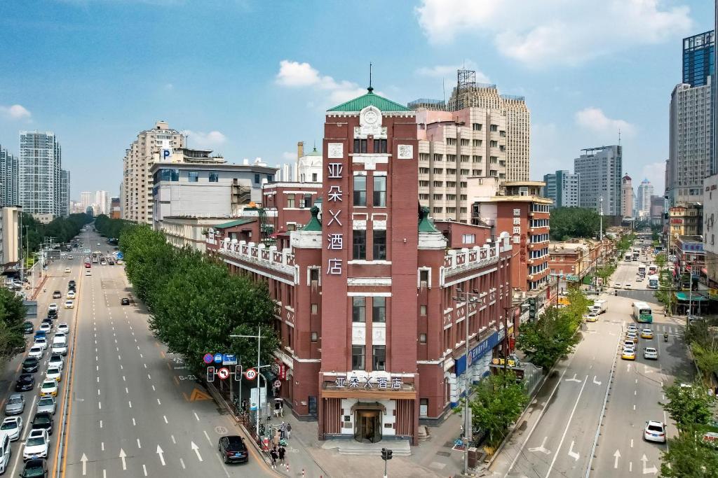 un gran edificio de ladrillo rojo con una torre de reloj en una ciudad en Atour X Hotel Zhongshan Road Shenyang Station en Shenyang