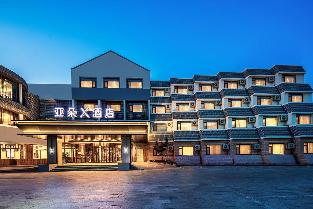 un grand bâtiment avec beaucoup de fenêtres dans l'établissement Atour X Hotel Yantai Penglai Pavilion, à Penglai