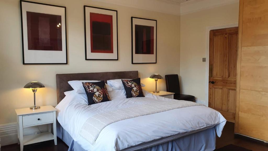 1 dormitorio con 1 cama con 2 lámparas y cuadros en la pared en Spacious Central London 2 Bedroom Mansion Block Apartment, en Londres
