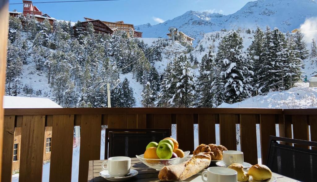 a table with a bowl of fruit and bread on a balcony at ALPS les ARCS 1950 Prince des Cimes, ski-in out,swimming pool, sauna, shoes dryer in Bourg-Saint-Maurice