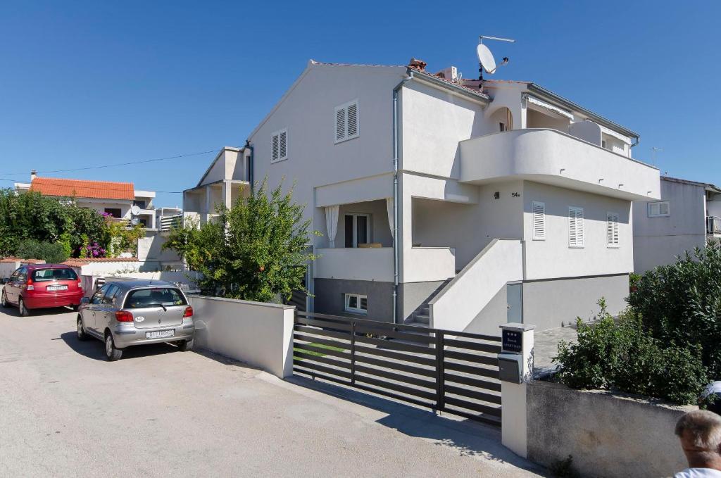 een wit huis met een auto ervoor geparkeerd bij Apartments Fila in Vodice